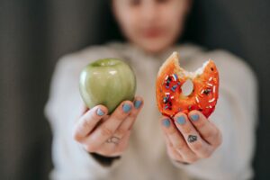 A woman holding an apple and a donut.
