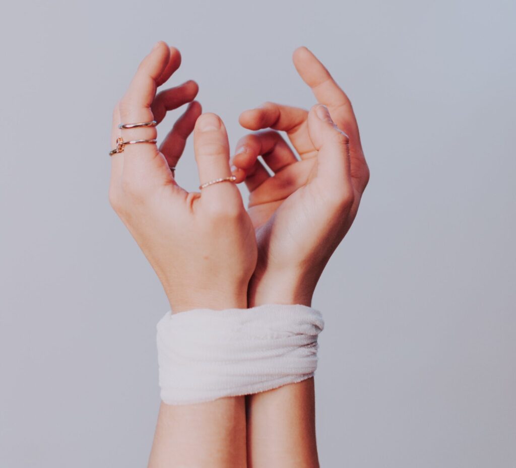 A woman's hands tightly wrapped in a white bandage symbolizing depression on a gray background.