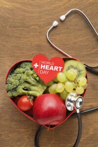 A heart shaped box with fruits and vegetables and a stethoscope.
