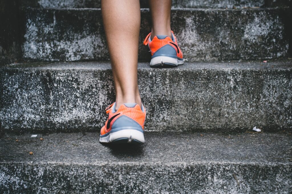 Person wearing orange sneakers walking up concrete stairs.